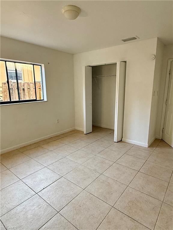 Unfurnished bedroom with a closet and light tile patterned flooring