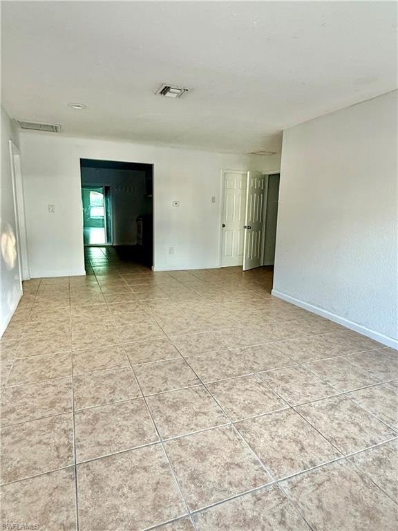 Empty room with light tile patterned floors and baseboards