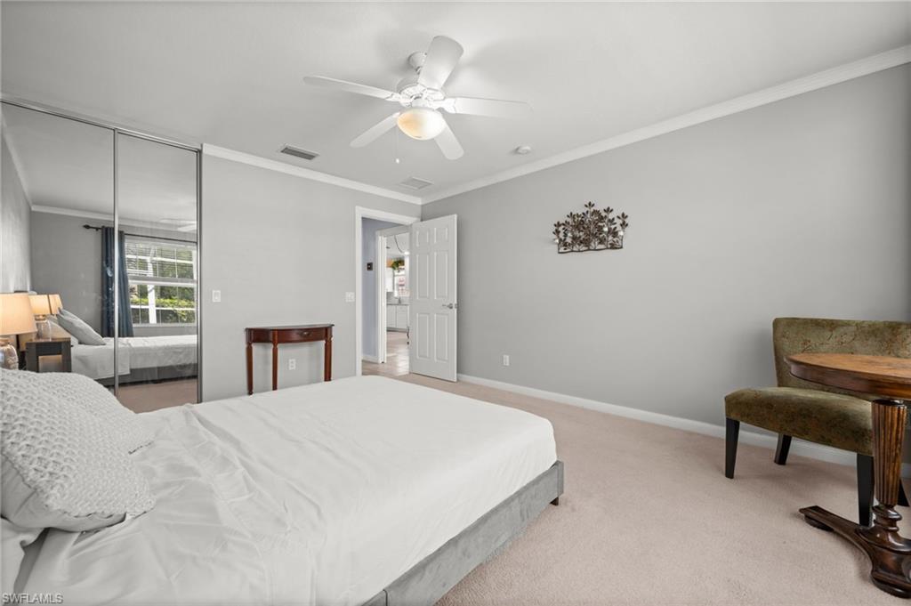 Bedroom with crown molding, light carpet, ceiling fan, and a closet