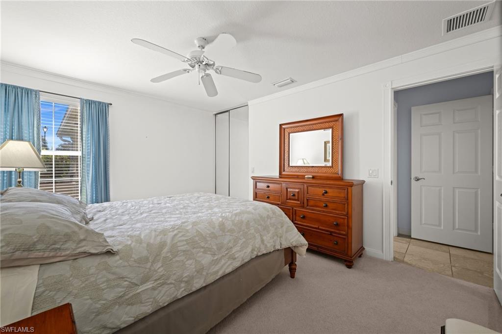 Bedroom featuring light colored carpet, a closet, ceiling fan, and crown molding