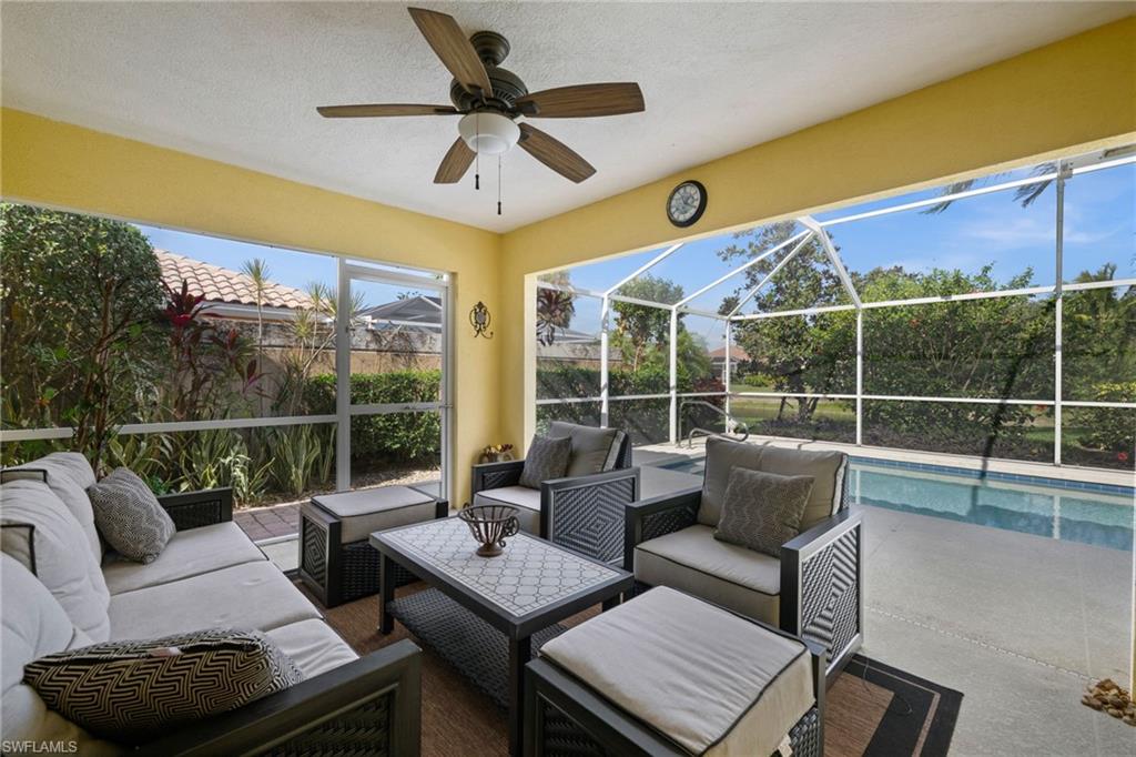 View of patio featuring glass enclosure, a sunroom, ceiling fan, and an outdoor living space