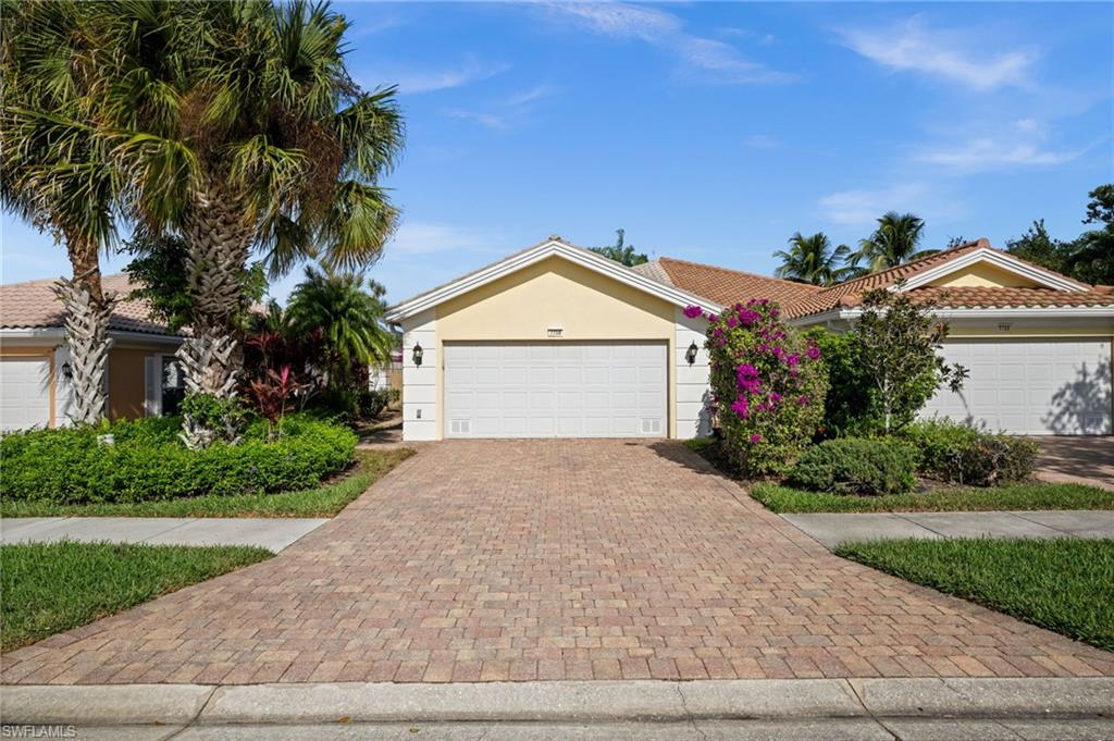 View of front of property with decorative driveway, stucco siding, a tile roof, and a garage