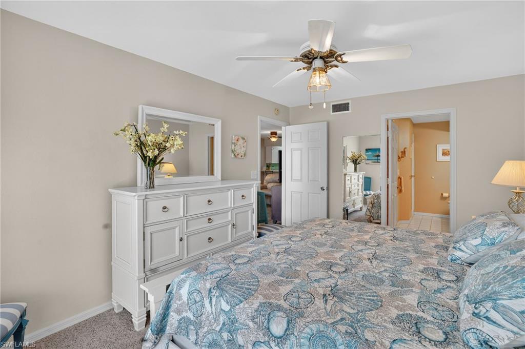 Bedroom with light carpet, ceiling fan, and ensuite bathroom