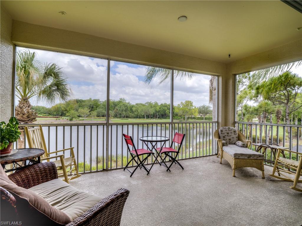 Sunroom featuring a water view, view of wooded area, carpet, and plenty of natural light