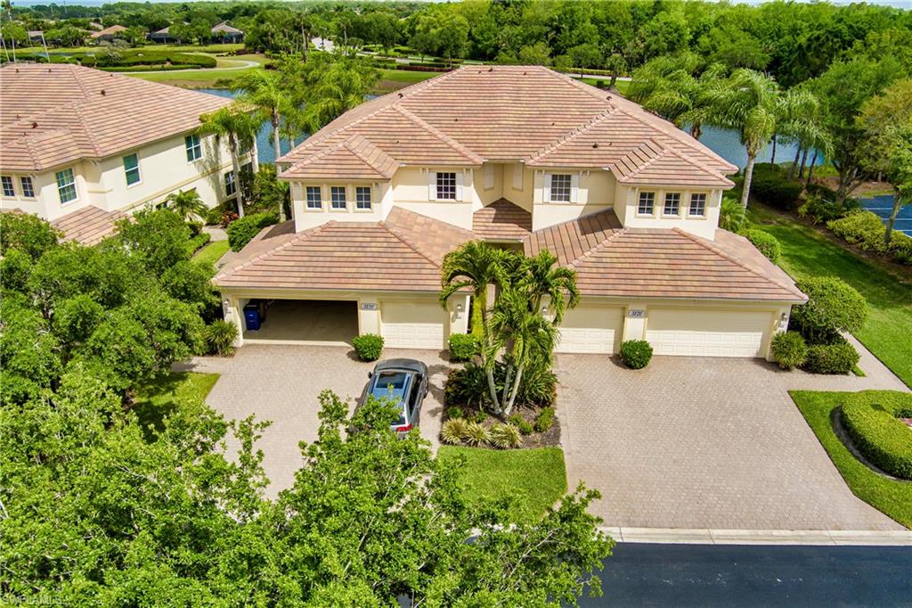 View of front of house with stucco siding, a water view, a tiled roof, decorative driveway, and view of wooded area