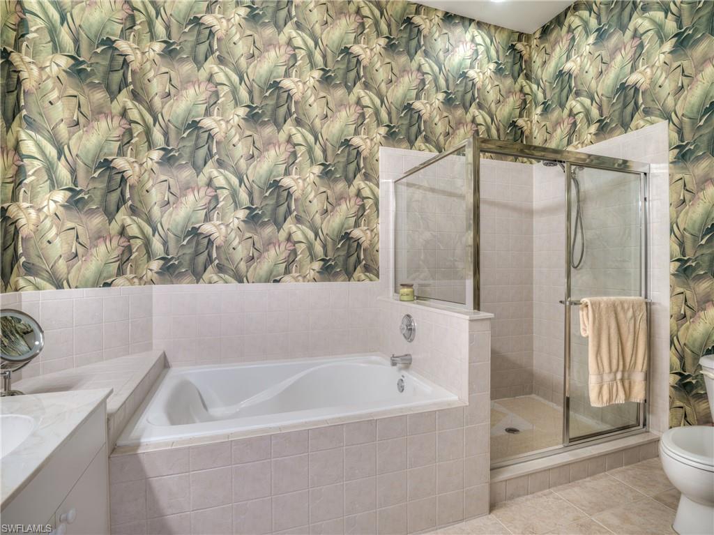 Full bathroom featuring wallpapered walls, a stall shower, a bath, vanity, and tile patterned floors