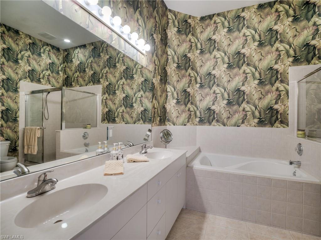 Full bath with a garden tub, wallpapered walls, double vanity, a stall shower, and light tile patterned floors