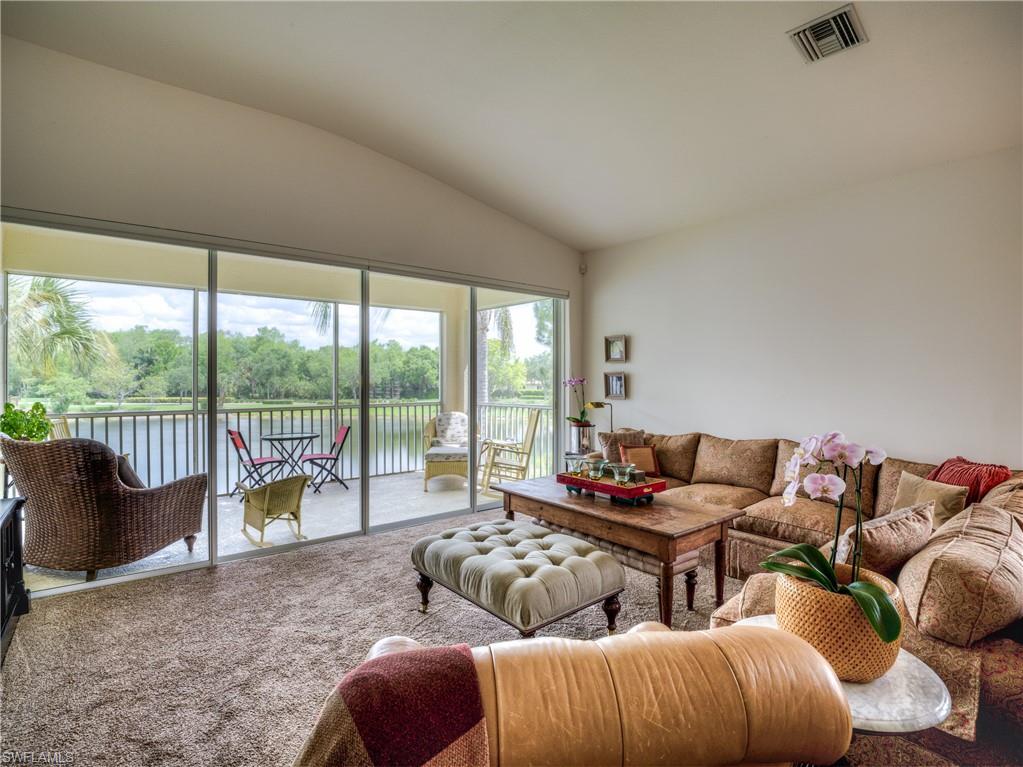 Carpeted living room featuring lofted ceiling, a water view, and view of wooded area