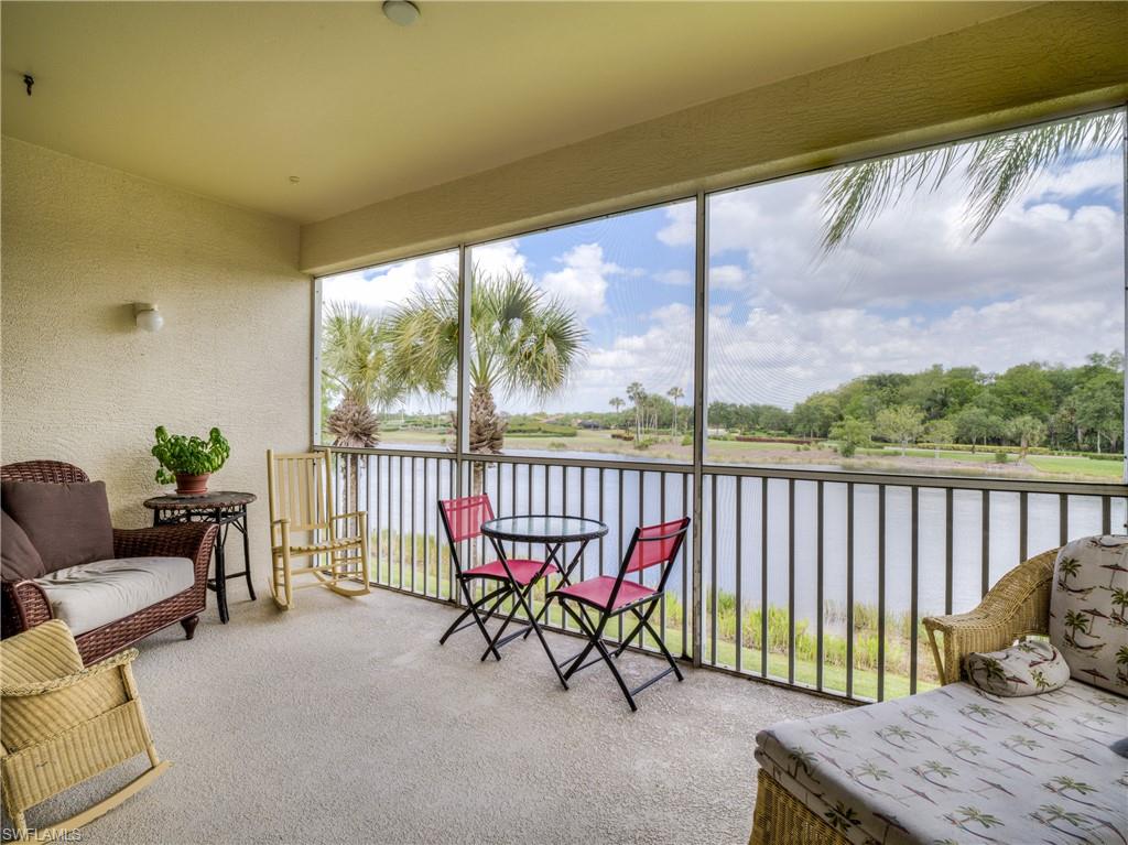 Sunroom / solarium with a textured wall, a water view, and carpet