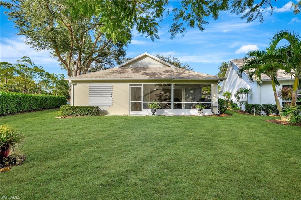 Back of property with a yard, a sunroom, and stucco siding