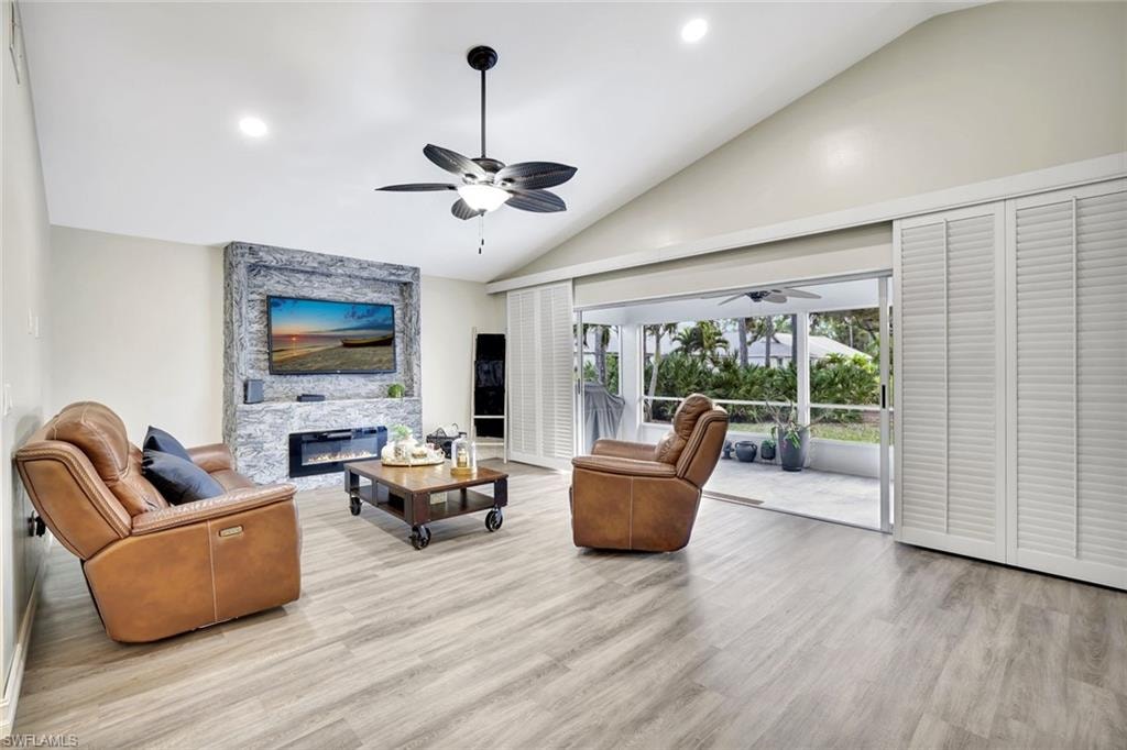 Living room featuring recessed lighting, light wood-style flooring, a fireplace, high vaulted ceiling, and ceiling fan