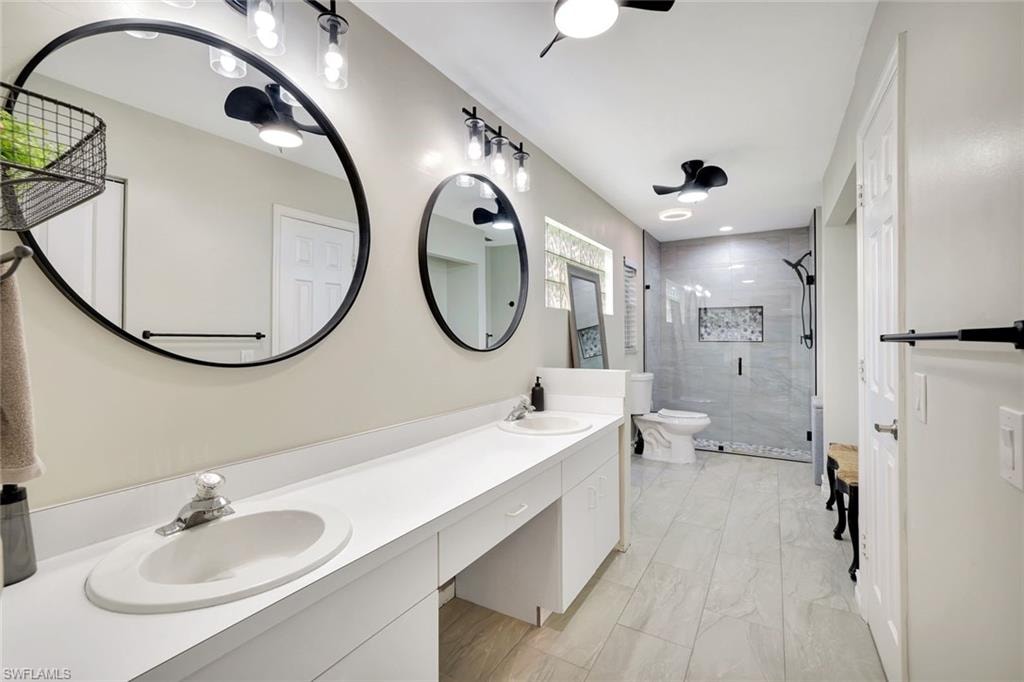 Bathroom featuring double vanity, a shower stall, and light marble finish flooring