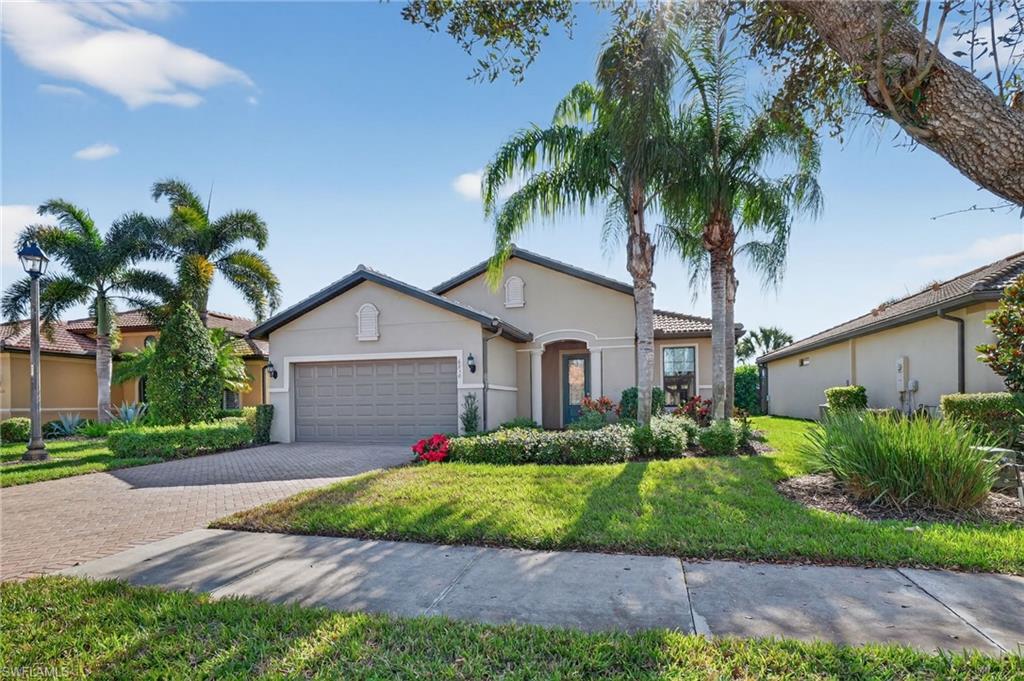 Mediterranean / spanish-style house with stucco siding, a front yard, a garage, and decorative driveway