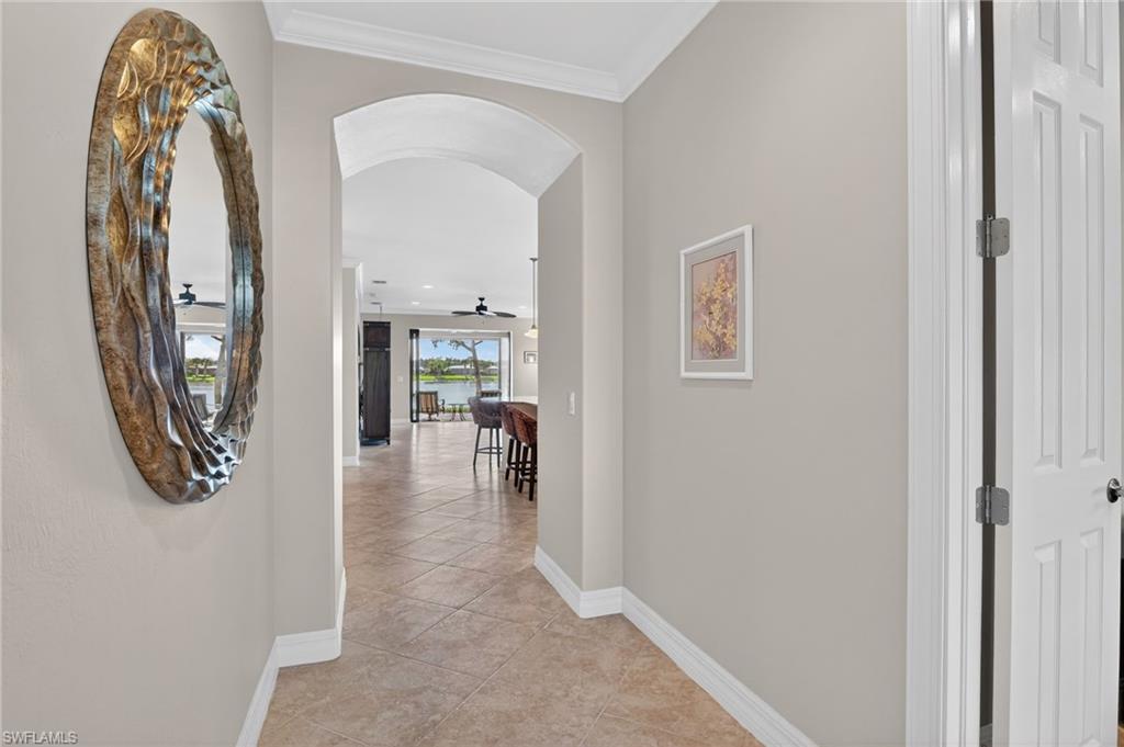 Corridor featuring arched walkways, and rounded edges, light tile patterned floors, and ornamental molding