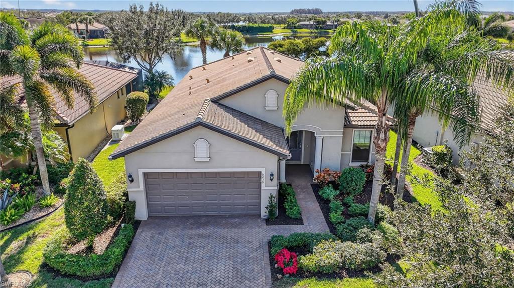 View of front of home with stucco siding, a garage, decorative driveway, and a water view