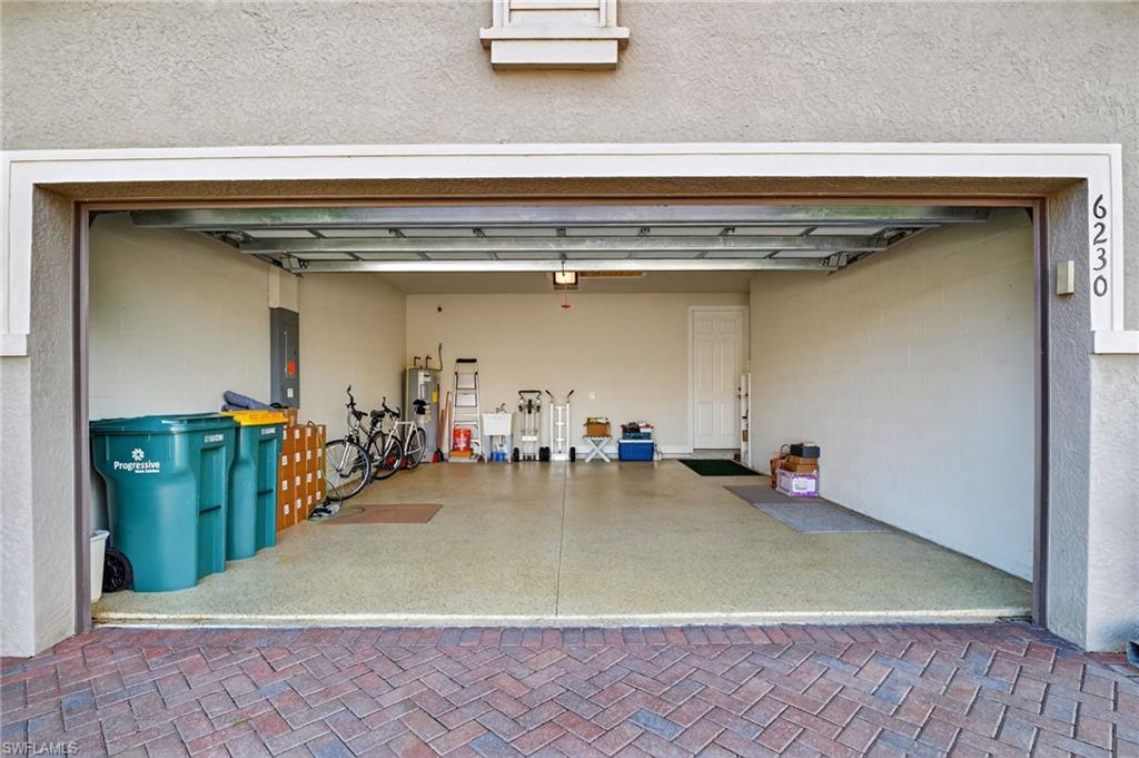 Garage featuring electric panel, water heater, and concrete block wall