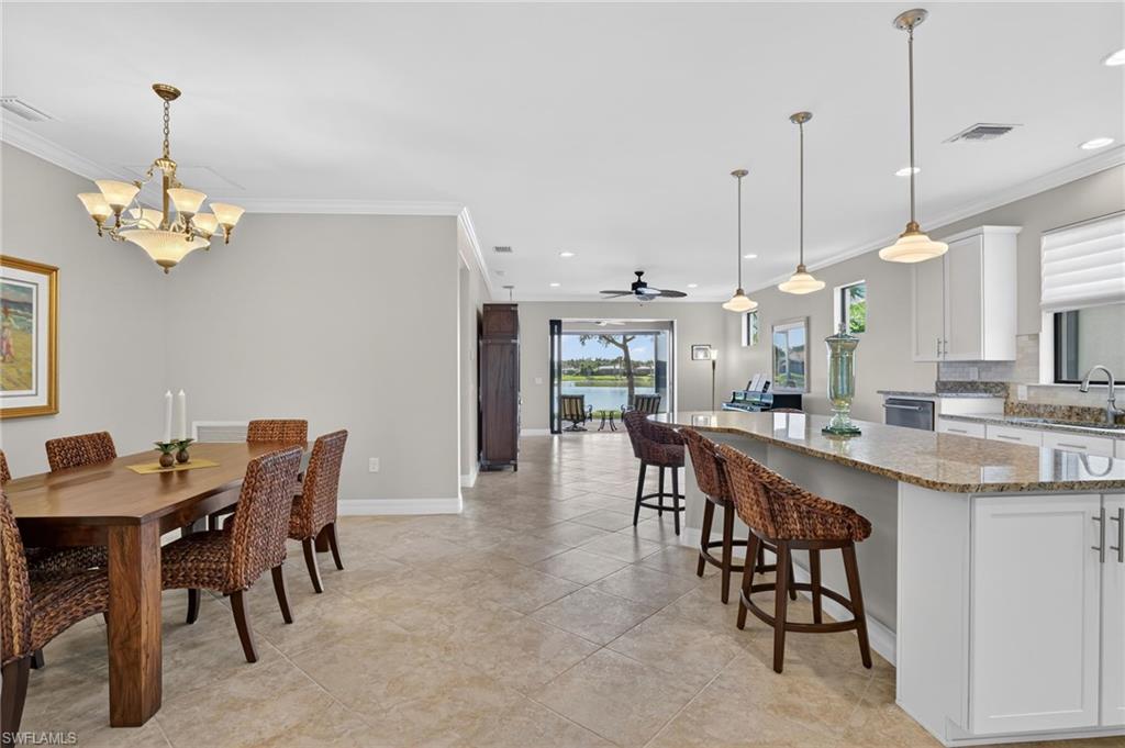 Dining area with crown molding, a ceiling fan, a chandelier, recessed lighting, and a water view