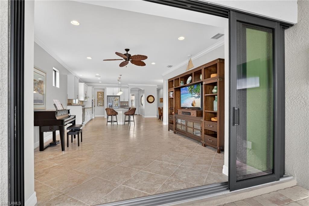 Living room with crown molding, ceiling fan, recessed lighting, and light tile patterned flooring