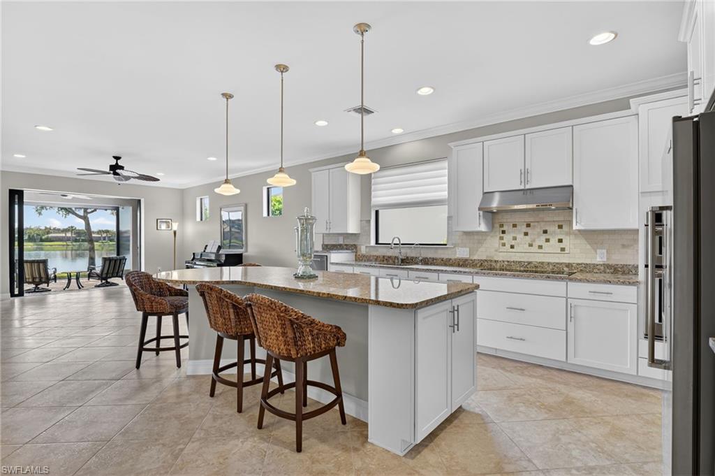 Kitchen featuring white cabinetry, a kitchen island, a breakfast bar, pendant lighting, and crown molding