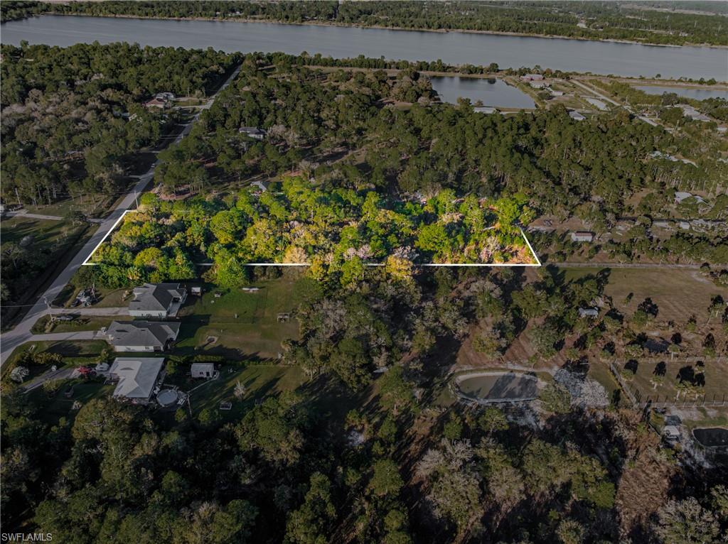 Aerial view of property and surrounding area with property parcel outlined and a nearby body of water