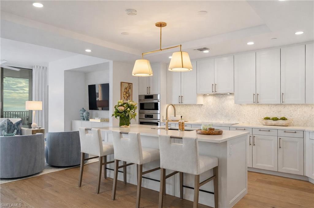 Kitchen with pendant lighting, backsplash, white cabinetry, recessed lighting, and a breakfast bar - Virtually Edited Image