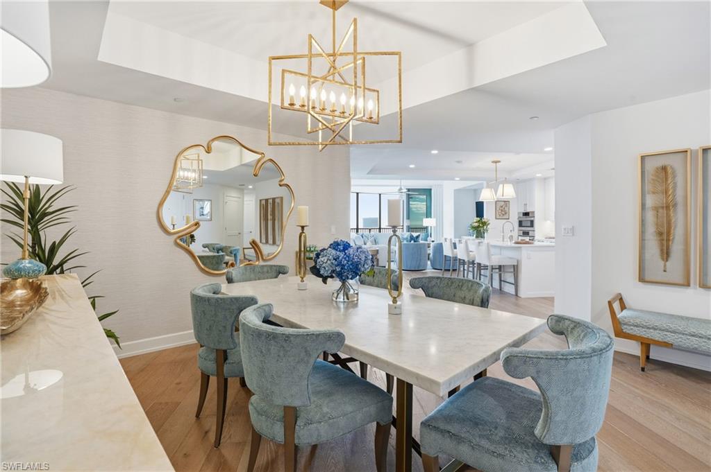 Dining room featuring a raised ceiling, light wood-style flooring, and recessed lighting - Virtually Edited Image