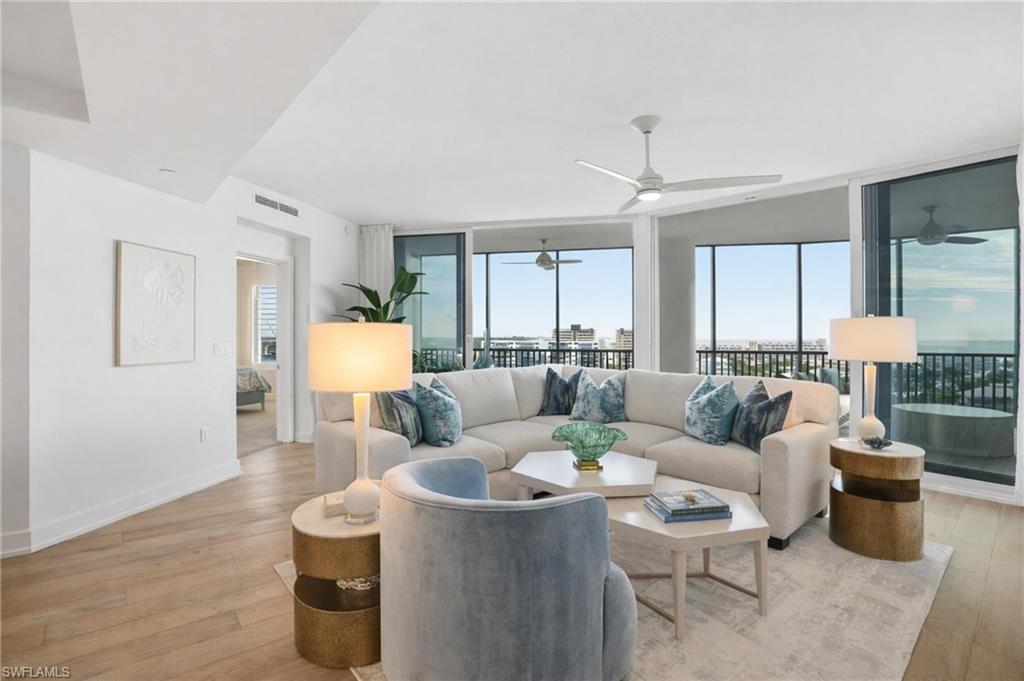 Living area featuring expansive windows, healthy amount of natural light, and light wood finished floors - Virtually Edited Image