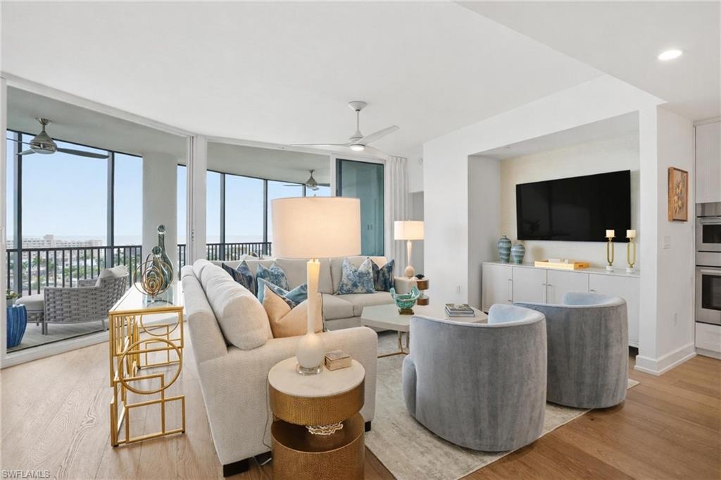 Living room featuring floor to ceiling windows and light wood-style flooring - Virtually Edited Image
