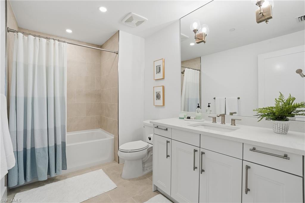 Bathroom featuring vanity, shower / bath combination with curtain, light tile patterned floors, and recessed lighting - Virtually Edited Image