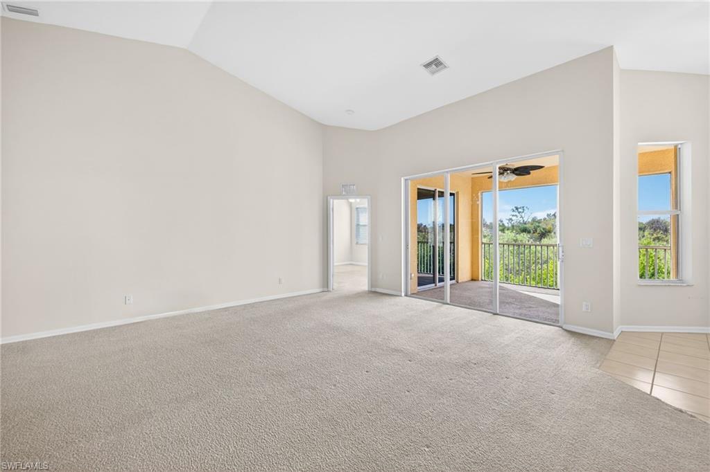 Carpeted spare room featuring vaulted ceiling and baseboards