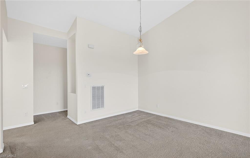 Carpeted spare room with lofted ceiling and baseboards