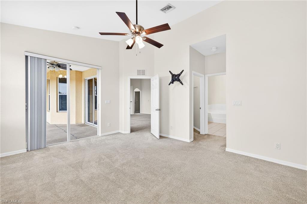 Unfurnished bedroom with light carpet, ceiling fan, and ensuite bathroom