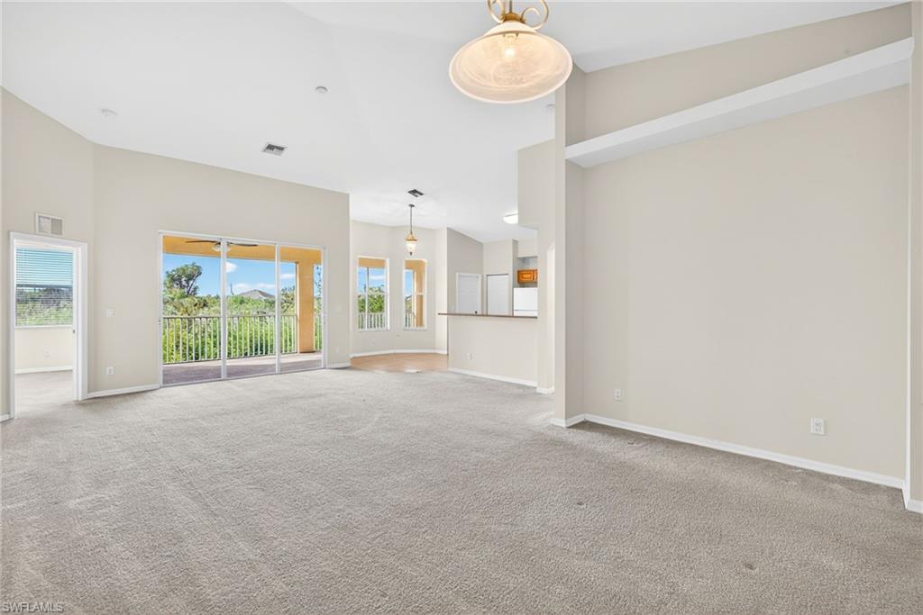 Spare room featuring carpet flooring and high vaulted ceiling