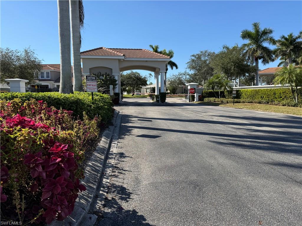 View of asphalt road featuring curbs and a gated entry
