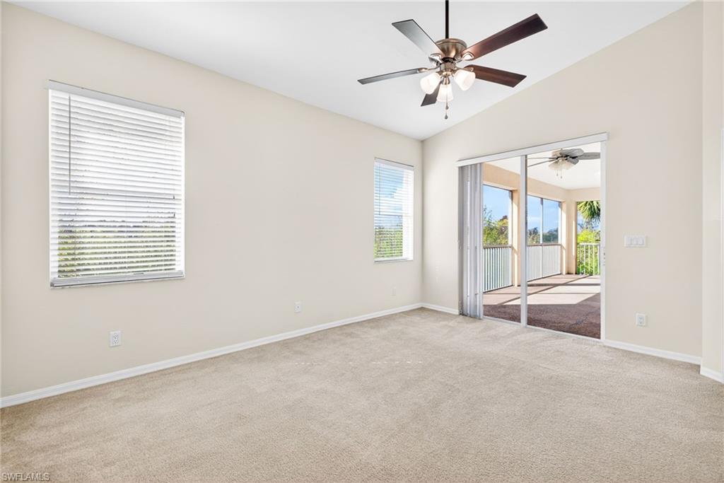Empty room with lofted ceiling, light carpet, and a ceiling fan