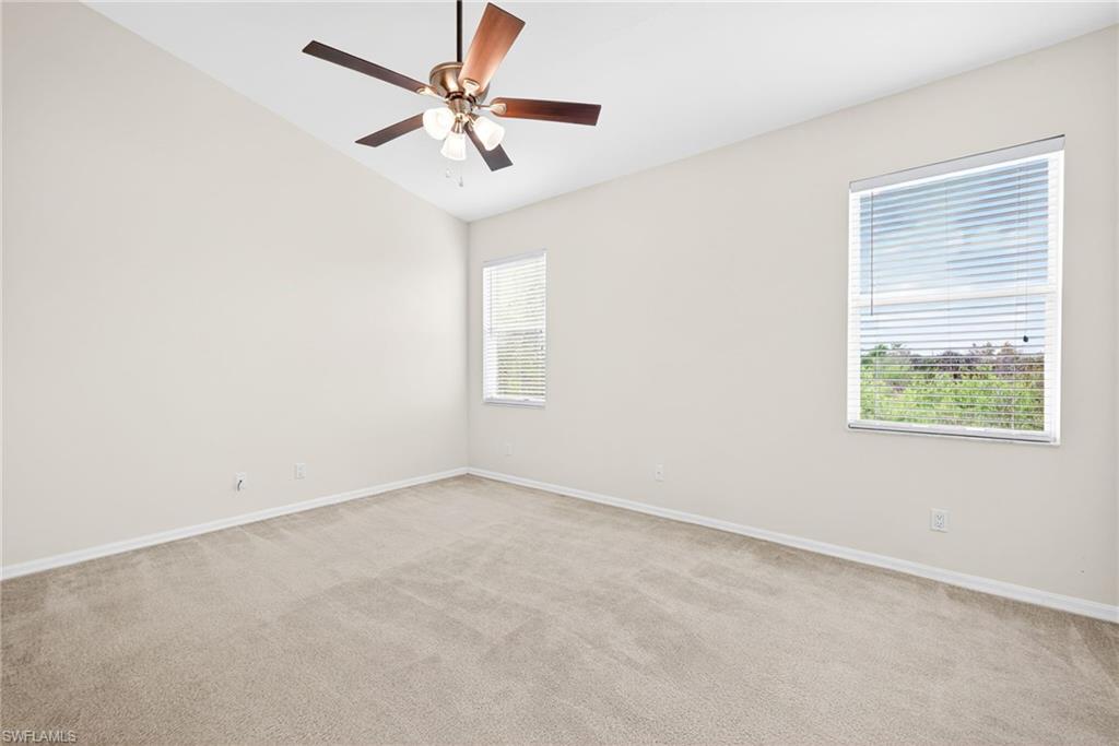 Unfurnished room featuring light colored carpet, vaulted ceiling, and ceiling fan