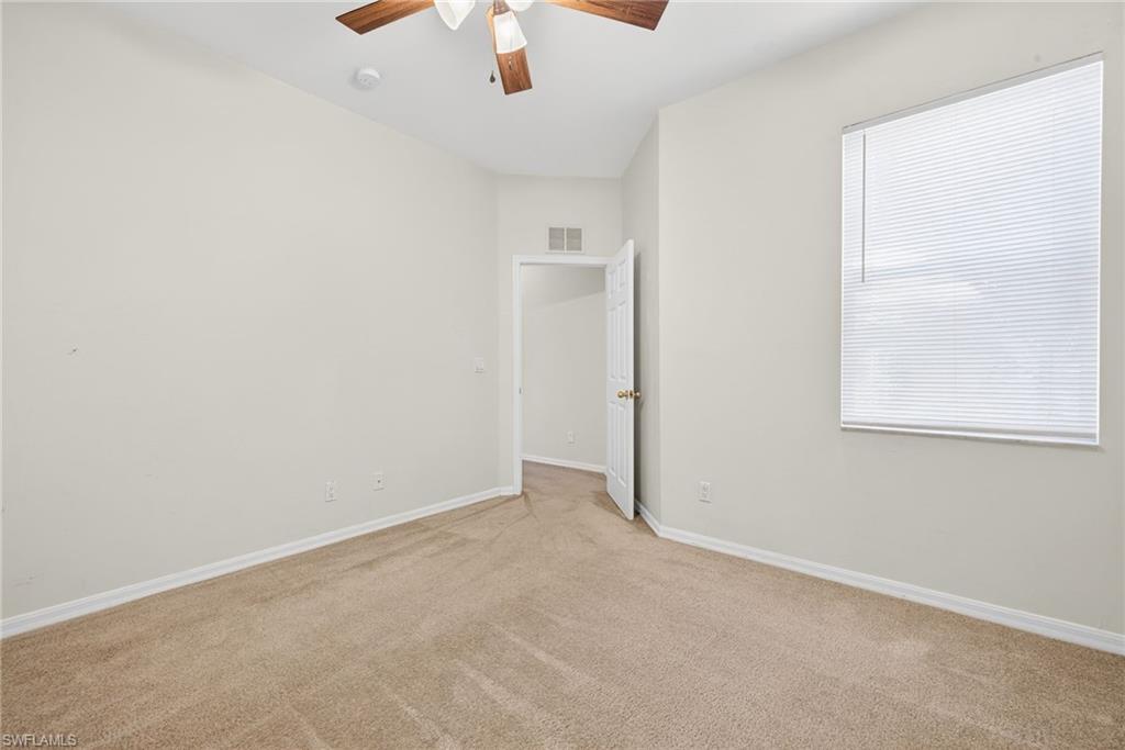 Carpeted spare room featuring ceiling fan and baseboards