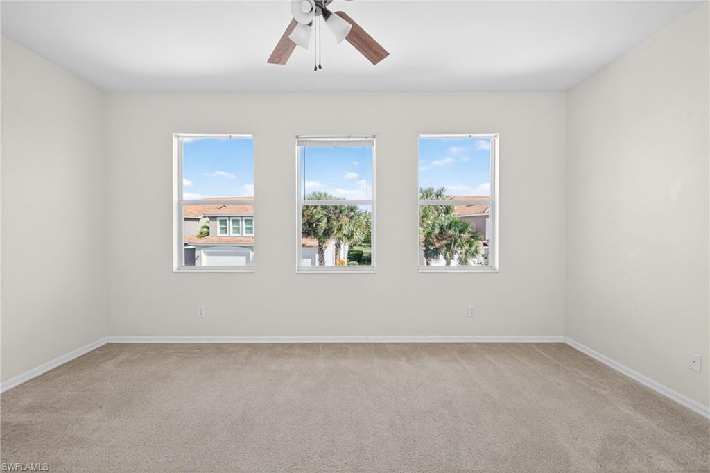 Unfurnished room featuring plenty of natural light, light carpet, and a ceiling fan