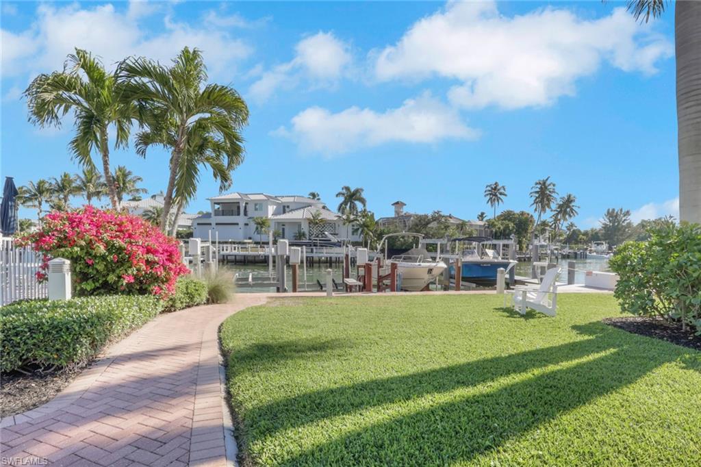 View of property's community with a yard, boat lift, a boat dock, and a water view