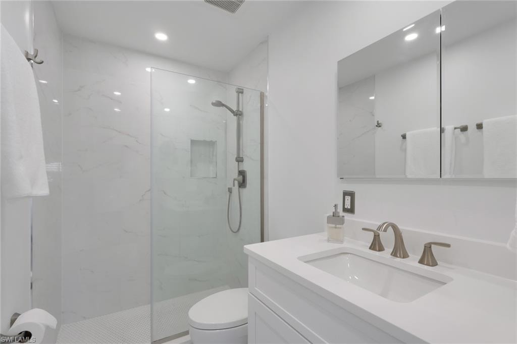 Bathroom with vanity and a marble finish shower