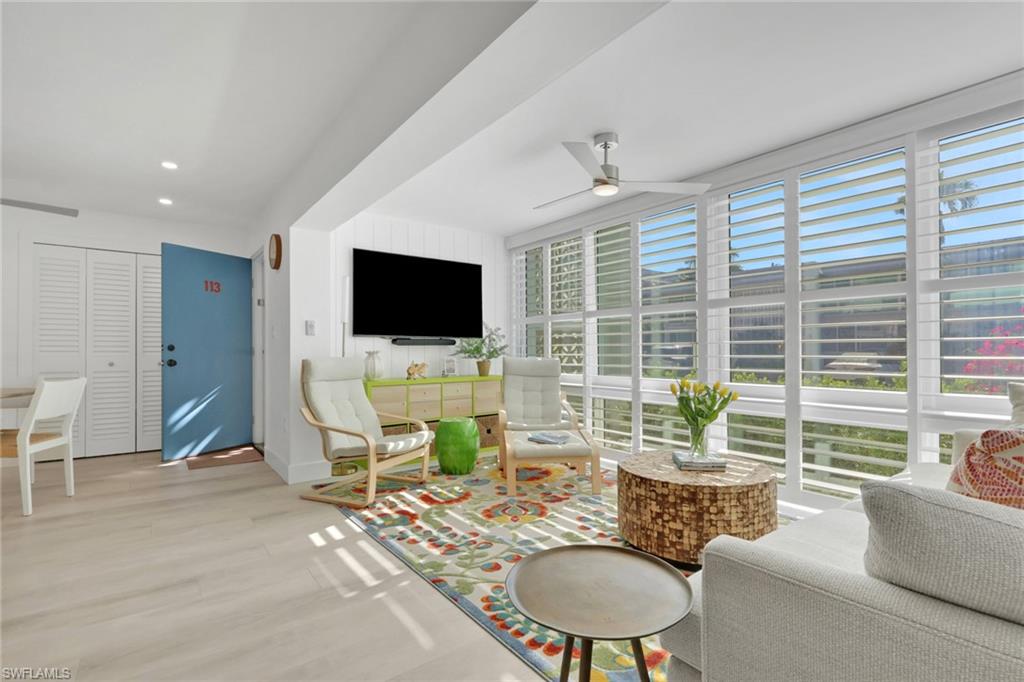 Living area featuring a ceiling fan, wood finished floors, expansive windows, and recessed lighting