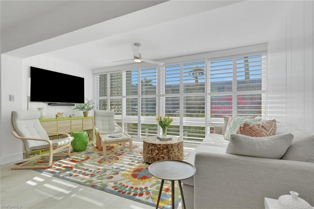 Living area with plenty of natural light, ceiling fan, and wooden walls