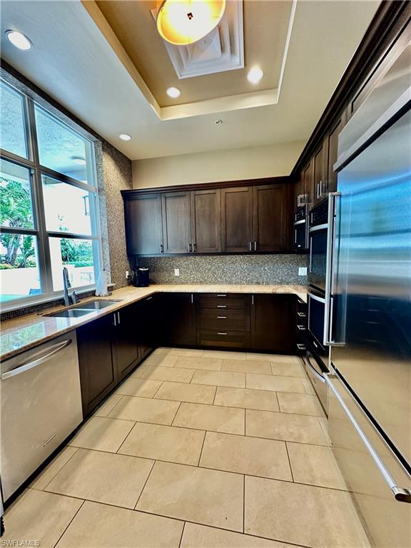 Kitchen featuring light tile patterned floors, stainless steel appliances, sink, and decorative backsplash