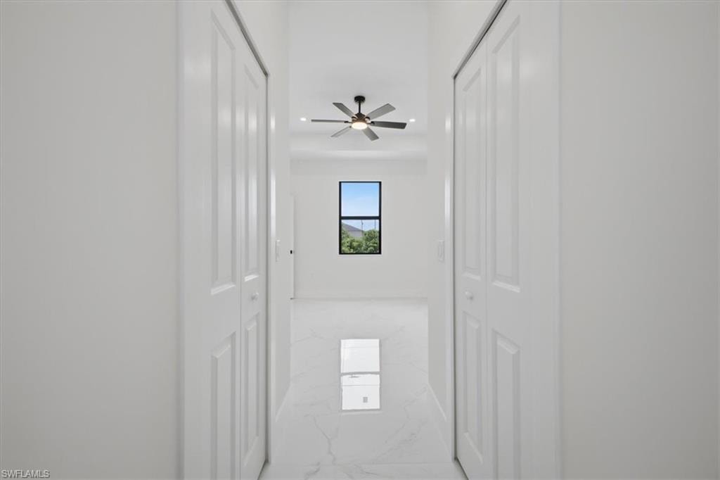 Hallway featuring white bi-fold doors, recessed lighting, and large format tile flooring