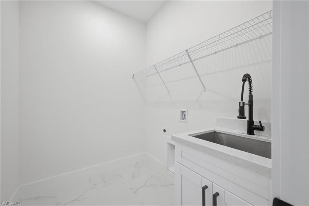 Utility room featuring a built-in sink with a matte black faucet, white cabinetry, and white countertop