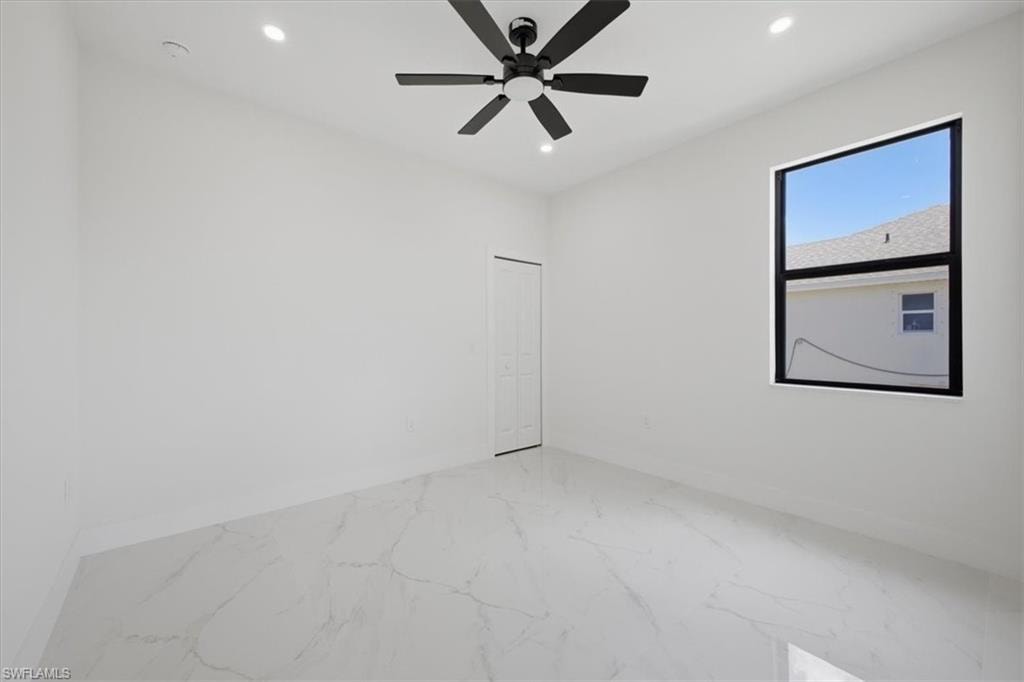 Bright interior space featuring large format marble-look tile flooring, a modern black ceiling fan, and recessed lighting