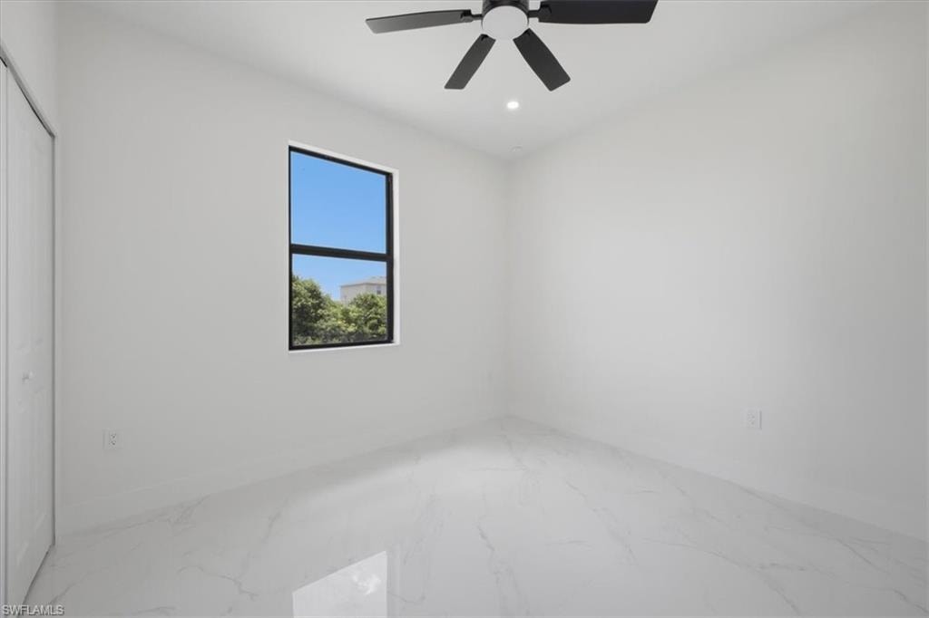 Bright room featuring a square window with dark framing, white walls, and white tile flooring