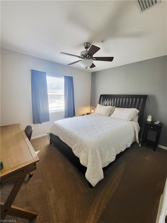 Bedroom with ceiling fan and dark colored carpet