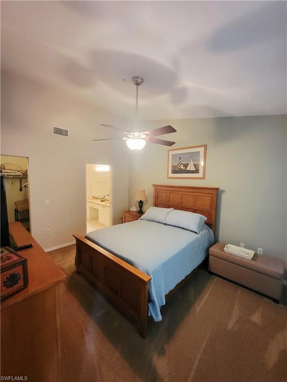 Bedroom featuring a ceiling fan, carpet, vaulted ceiling, connected bathroom, and a spacious closet