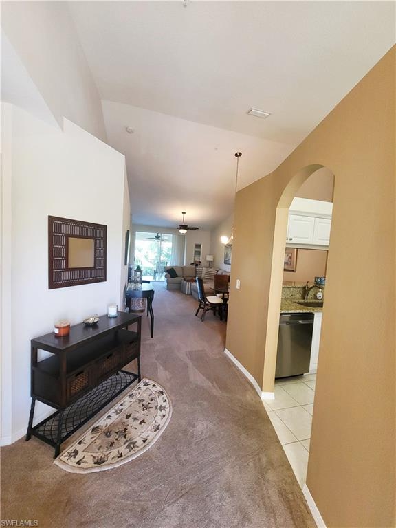 Hallway featuring light carpet and arched walkways